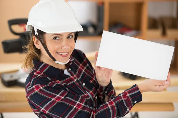 空白のカードを持っている女性建設労働者 — ストック写真
