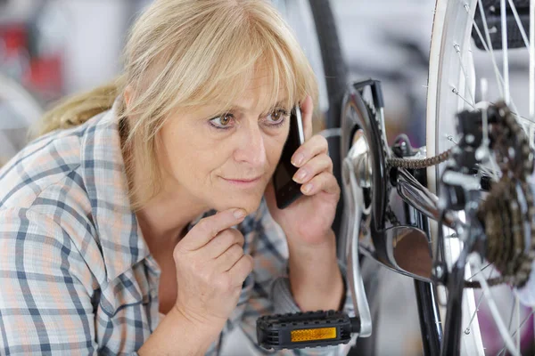 전화를 여자가 자전거를 확인하는 — 스톡 사진