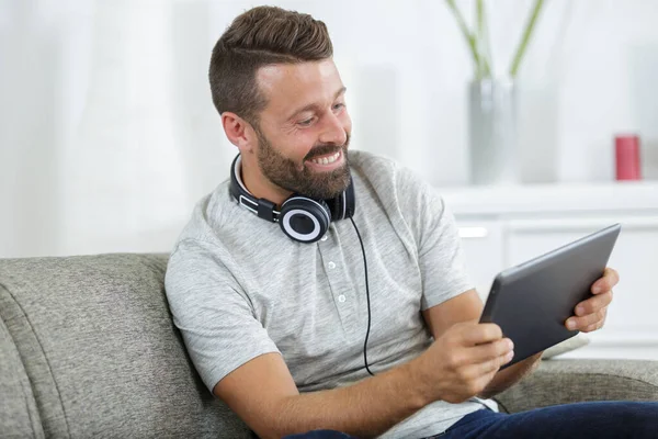 Mann Auf Sofa Mit Kopfhörer Und Digitalem Tablet — Stockfoto