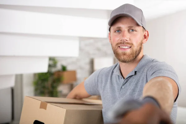 微笑年轻送货的男子抱着一个纸板箱 — 图库照片