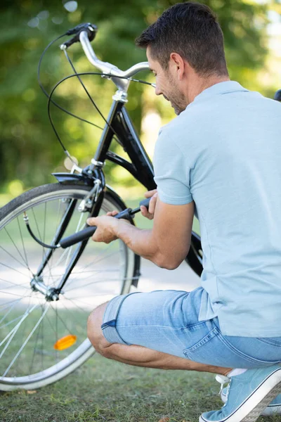 男は屋外で自転車の車輪を汲み上げ — ストック写真