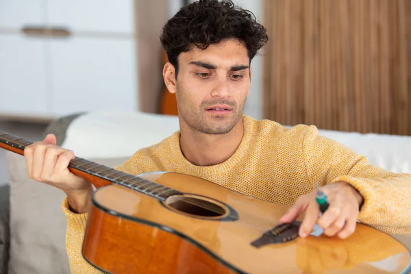 handsome man repairing an acoustic guitar