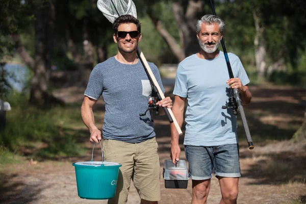 二人の男が漁具を持って歩道を歩き — ストック写真