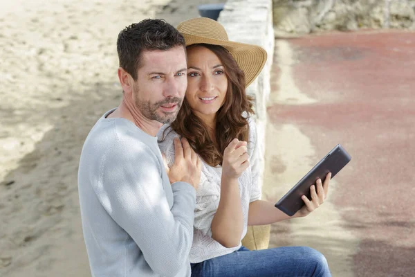 おしゃれな男性と女性のぼやけたビーチに対してタブレット — ストック写真
