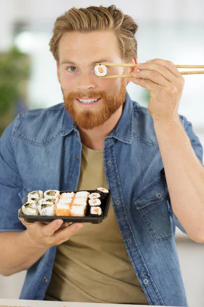 young man eating sushi on white background