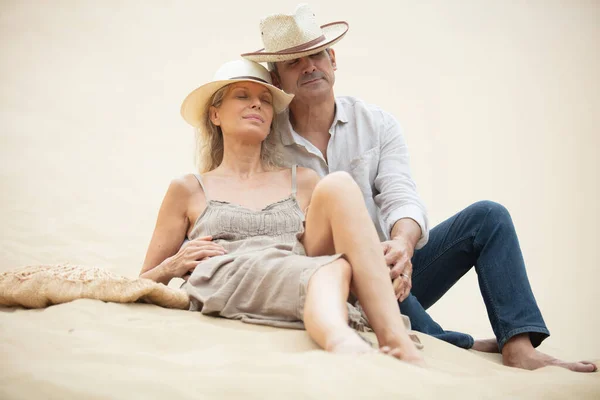 成熟した夫婦が砂丘の上に座っている姿を — ストック写真