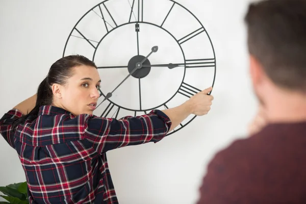 Een Koppel Hangend Een Klok Aan Muur — Stockfoto