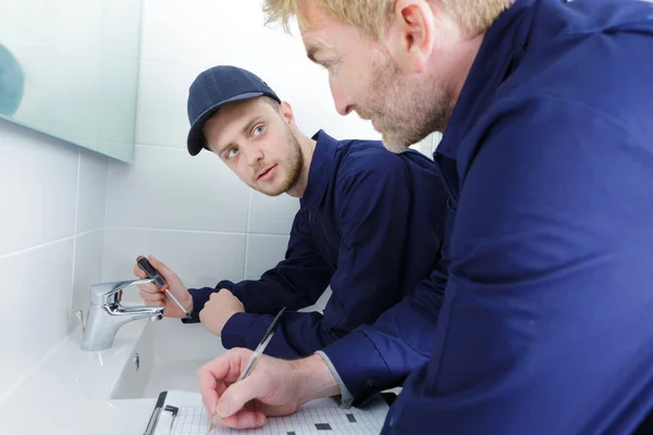 男性訓練生配管工が浴室でタップ作業をし — ストック写真