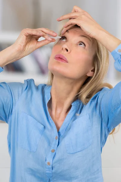 一个女人把眼药水放在她的眼睛里 — 图库照片