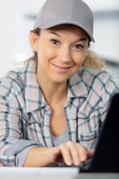 ノートパソコンを使って帽子をかぶった女性の手作業員が — ストック写真