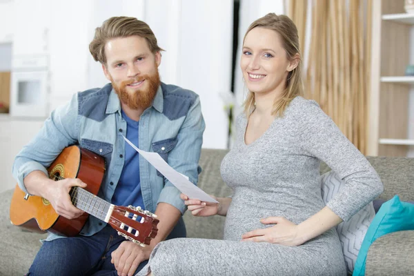 Těhotná Žena Držení List Hudba Pro Manžela Hraní Kytaru — Stock fotografie