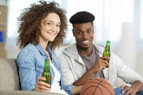 在家里看电视上的篮球比赛的快乐的年轻夫妇 — 图库照片