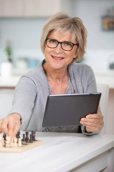 Senior Vrouw Schaken Het Houden Van Een Tablet — Stockfoto