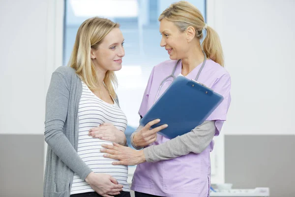 怀孕的女性病人与优秀的资深医生交谈 — 图库照片