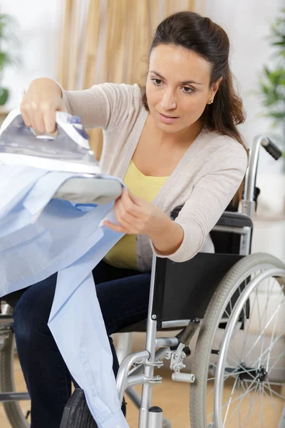 Kobieta Wózku Inwalidzkim Podczas Prasowania Domu — Zdjęcie stockowe