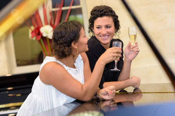 Две Женщины Пьющие Шампанское Стояли Фортепиано — стоковое фото
