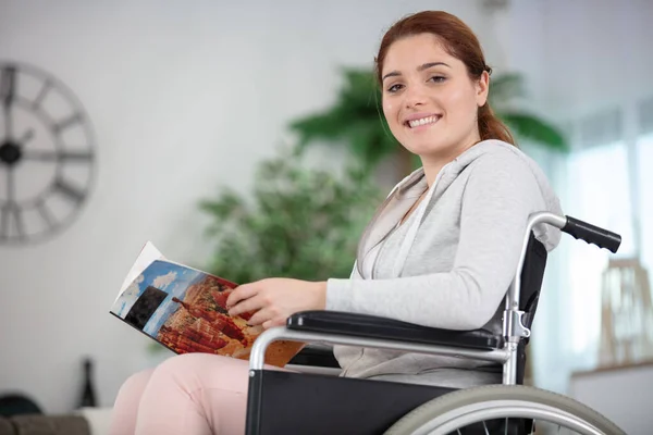 車椅子に座って雑誌を持っている障害者の女性は — ストック写真