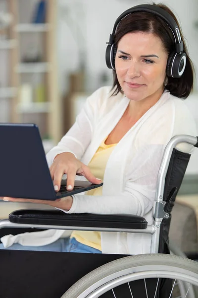 Ελκυστική Γυναίκα Αναπηρικό Καροτσάκι Χρήση Φορητού Υπολογιστή Και Ακουστικών — Φωτογραφία Αρχείου