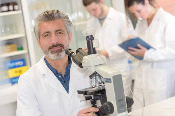 男科学研究员在实验室里用显微镜 — 图库照片