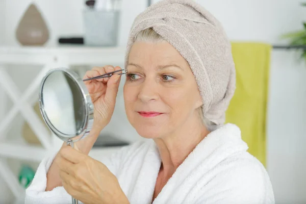 Äldre Kvinna Som Plockning Ögonbrynen Med Pincett — Stockfoto