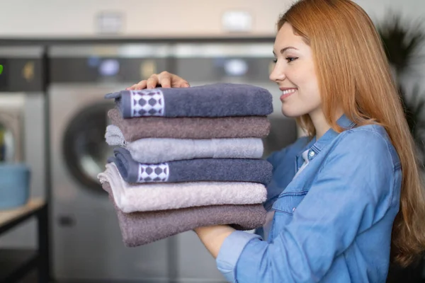 Stock image beautiful young woman with stack of clean towels at home