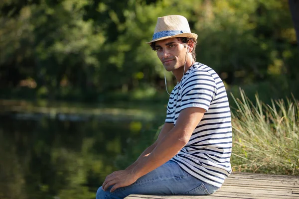 Молодий Чоловік Відпочиває Слухати Музику Біля Озера — стокове фото