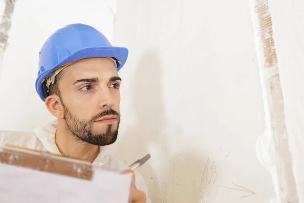 Bauunternehmer Auf Renovierungsbaustelle Schaut Auf Wand Gekritzelte Zettel — Stockfoto