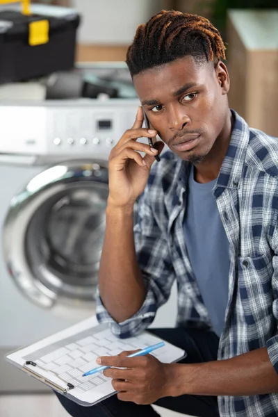 보드를 스마트폰으로 이야기하는 세탁기 수리공 — 스톡 사진