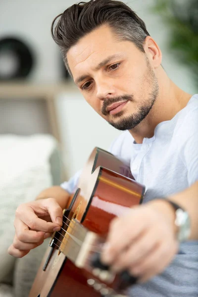 Joven Feliz Tocando Guitarra Sentado Sofá Casa — Foto de Stock