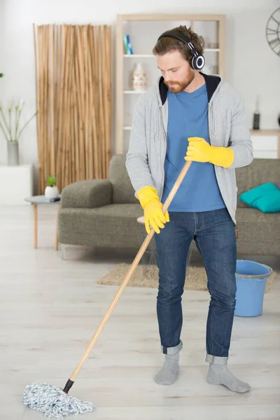 穿着黄色橡胶手套的英俊而集中的男人在打扫他的公寓 — 图库照片