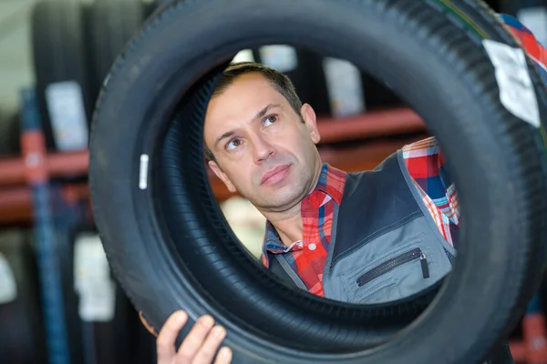 셔터들 앞에서 타이어를 들여다보고 기계공 — 스톡 사진