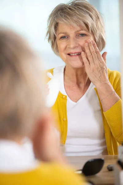 Elderly Woman Applying Moisturiser Her Cheek — Stock Photo, Image