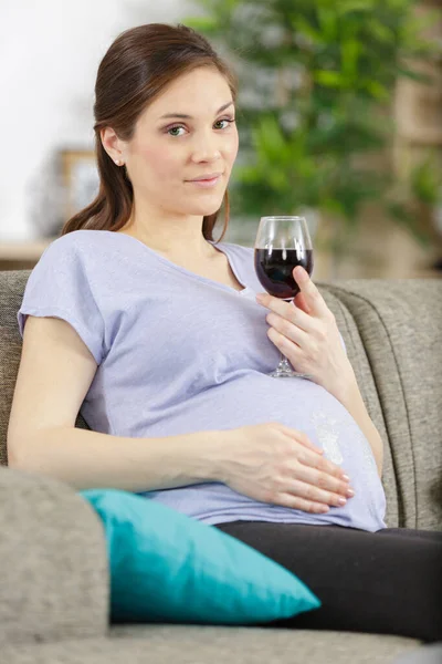 妊娠中の女性の飲み物グラスワインを家庭で笑顔 — ストック写真