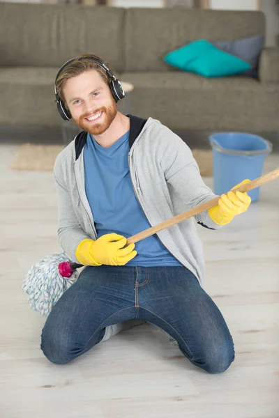 young domestic service man playing with mop a song