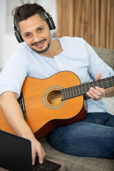 Mężczyzna Gra Gitarze Swoim Domu Pomocą Laptopa Słuchawki — Zdjęcie stockowe