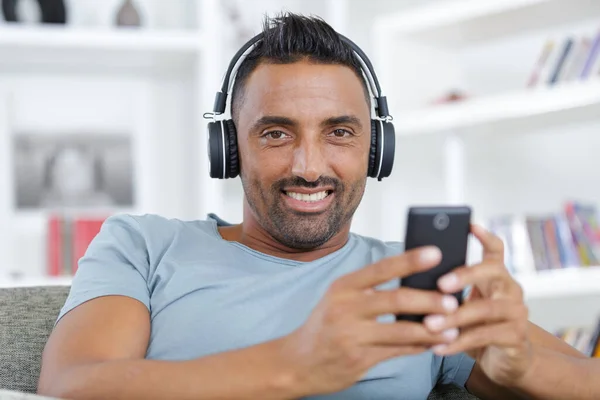 Homem Com Fones Ouvido Telefone Sorrindo Sofá Casa — Fotografia de Stock