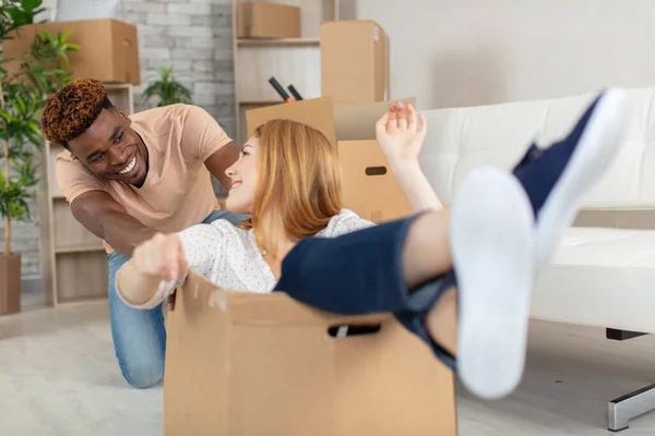 家の段ボール箱の上に座っている女性を押す男 — ストック写真