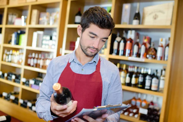 wine merchant holding bottle of wine and clipboard