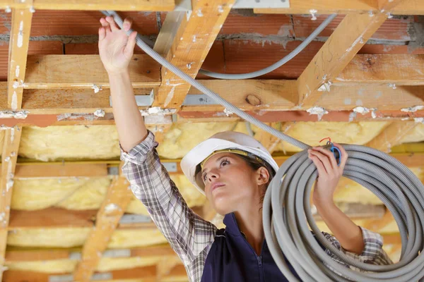 stock image female electrician installing pipes in ceiling