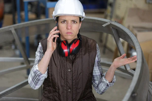 Mujer Desconcertada Una Fábrica Hablando Teléfono Inteligente —  Fotos de Stock