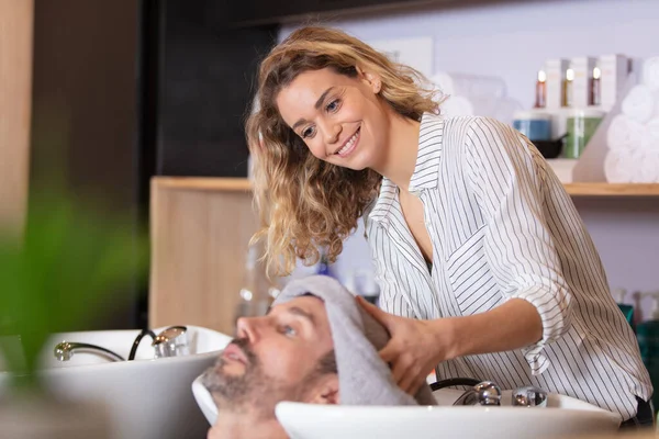 Fryzjer Uśmiechnięty Podczas Mycia Włosów Przystojnego Klienta — Zdjęcie stockowe