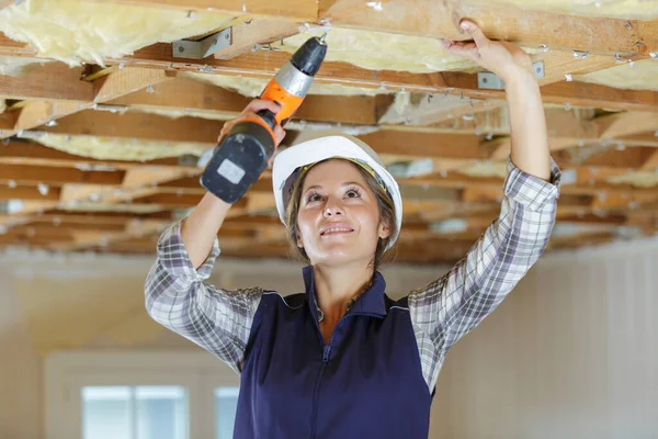 木の家でドリルを使う女性大工 — ストック写真
