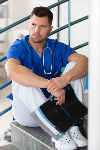病院の階段に座っている男性外科医を動揺させ — ストック写真