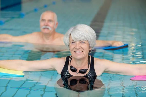 年长的夫妇在游泳池里游泳 — 图库照片