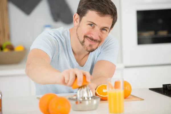 男はオレンジジュースを作ってる — ストック写真