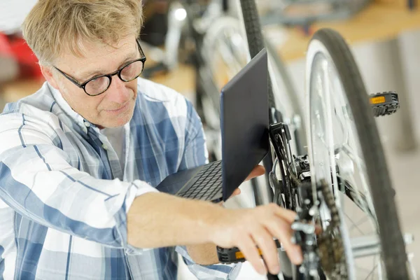 Fahrradreparateur Schaut Auf Laptop — Stockfoto