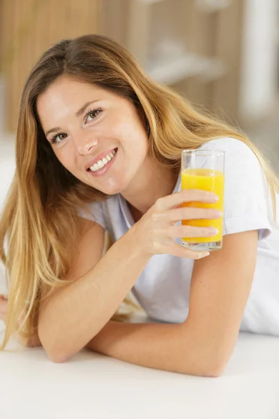 穿着黄色饮料的女人用玻璃杯喝橙汁 — 图库照片