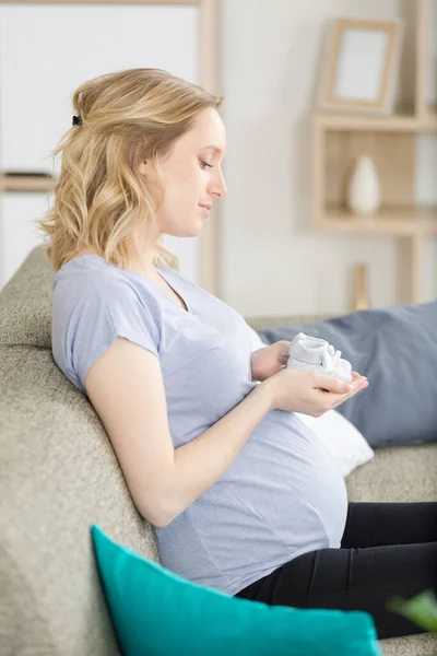 妊娠中の女性のお腹の小さなベビーシューズ — ストック写真