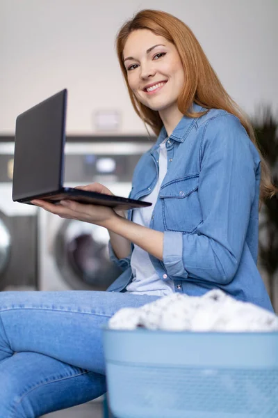 Trevlig Kvinna Kontrollera Tvättmaskinen Medan Arbetet Laptop — Stockfoto