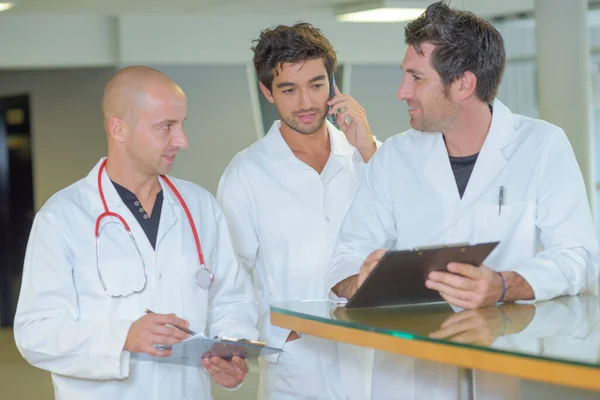 Three Male Doctors Holding Clipboards Conferring Together — Stock Photo, Image